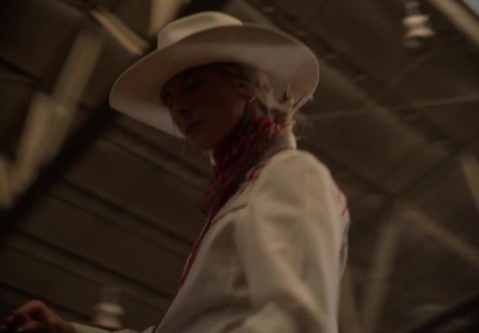Cowgirl rides a horse inside a stable