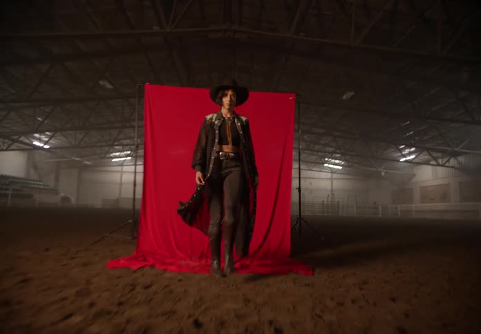 Woman walking and modeling in a rodeo arena in cowgirl attire