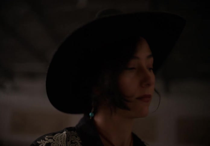 Woman standing in riding arena models a black cowboy hat