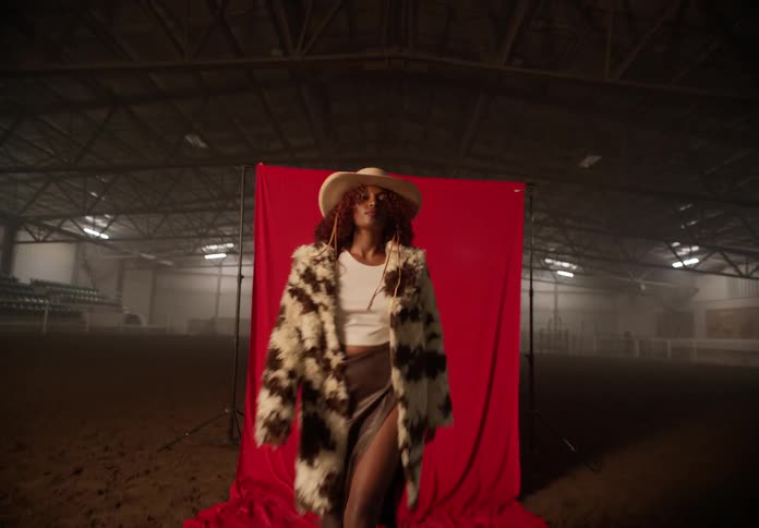 Woman modeling inside an arena in cowgirl attire