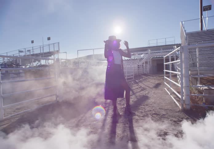 Cowgirl modeling in an openair arena and being presented with smoke