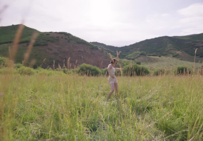 A woman dancing outdoors in a meadow during the day