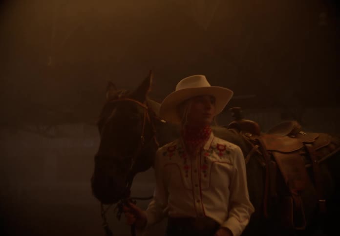 Person walking a horse inside a big barn during the day