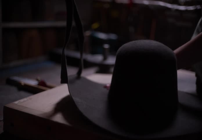 A person making a black hat in a studio