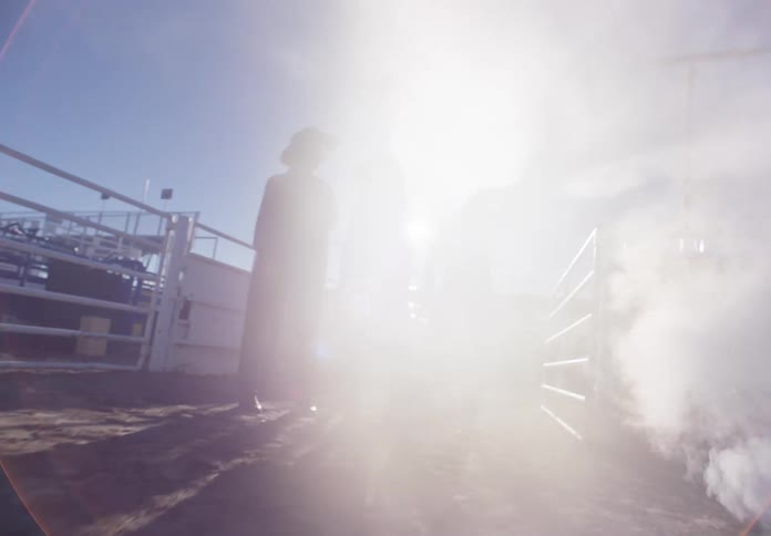 Three models standing in a rodeo arena with smoke passing beneath them