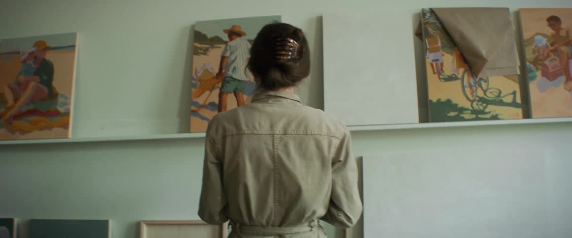 Woman standing up with her laptop in hand looking at art on the wall