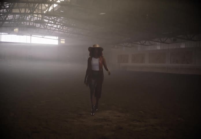 A woman in an empty building walks and models stylish clothing