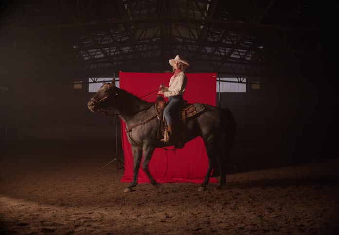 A woman riding a horse in an enclosed arena