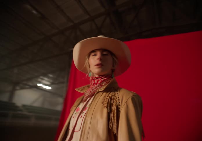 Woman models cowboy clothes on a large hangar