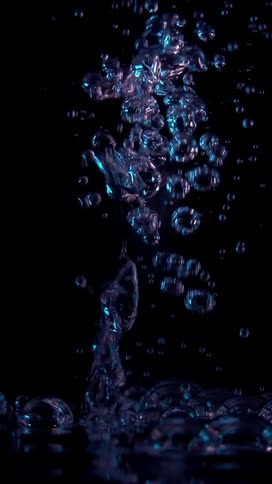 Jet emerging from water generating bubbles against a black background