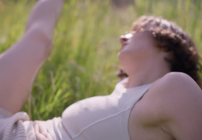 A young lady lying on the grass and dancing
