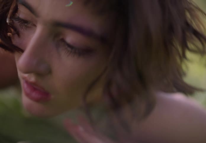 Portrait of a young woman dancing while lying in the middle of a field