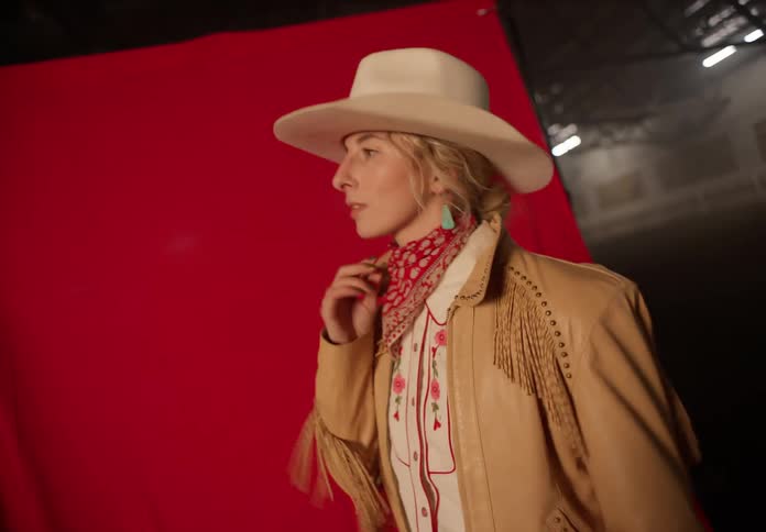 Portrait of a woman posing in a cowgirl hat and outfit
