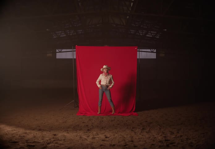 Woman modeling cowboy clothes inside a large hangar