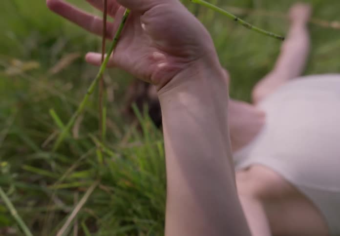 A woman holding field plants lying on the grass