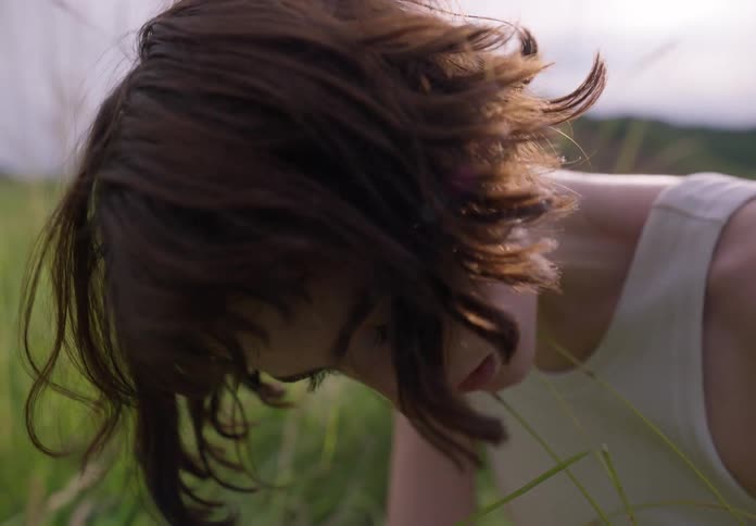 Portrait of a young woman sitting in the middle of a field in nature