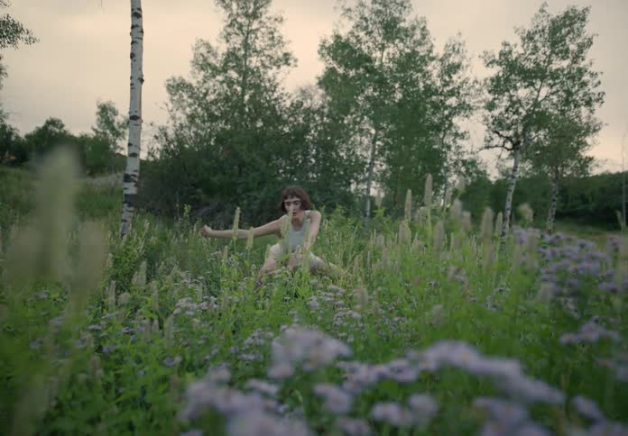 A woman dancing in the middle of a grass field