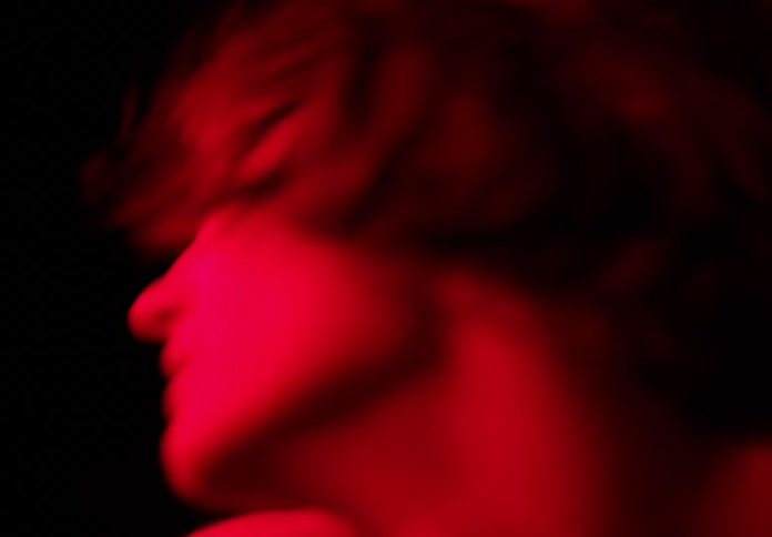 Portrait of a woman dancing at night with red light beneath her