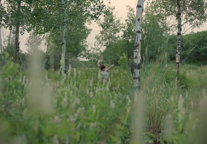 Woman dancing in the midst of a grassland in nature on a cloudy day