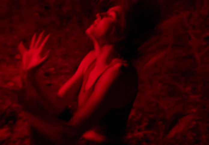 Woman dancing at night in the forest with red light shining from beneath her