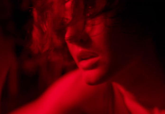A woman in the forest with a red florescent light looking all tired