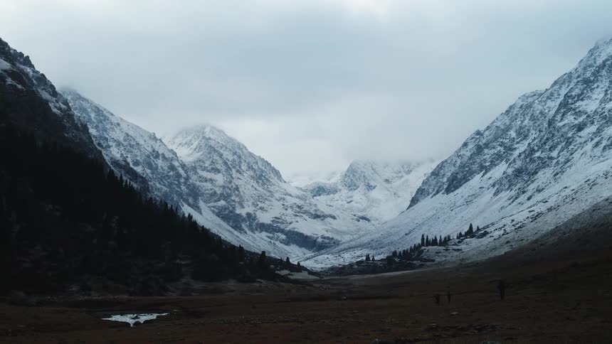 Panorama of a landscape in the middle of a field with snowcovered mountains on a cloudy day