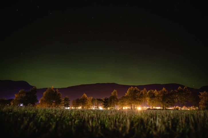 Time lapse of green northern lights over a town