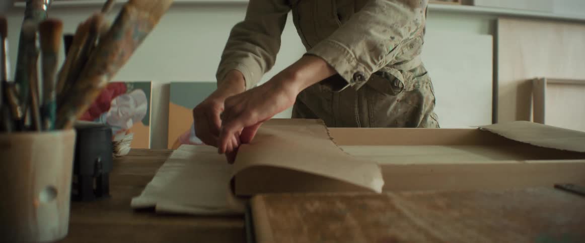 Woman wrapping a painting on the table