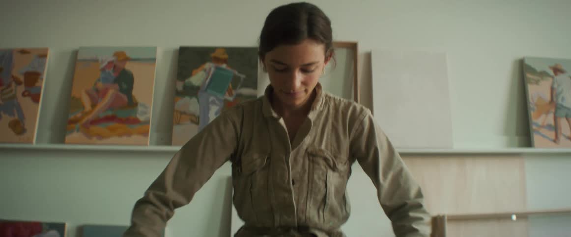 Woman stands at table in front of wall paintings