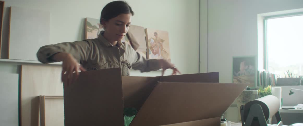 A woman puts plastic inside a cardboard box and closes it
