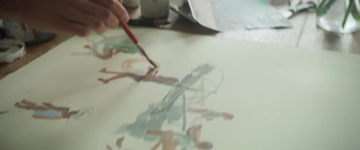 Closeup of a womans hands painting a canvas on a table