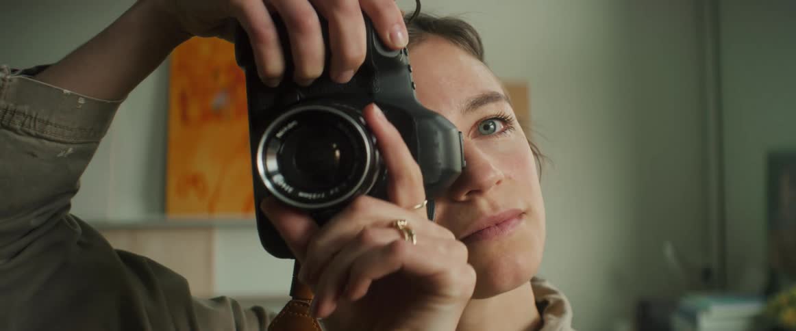 A woman holds up a professional camera checking it before taking a photo