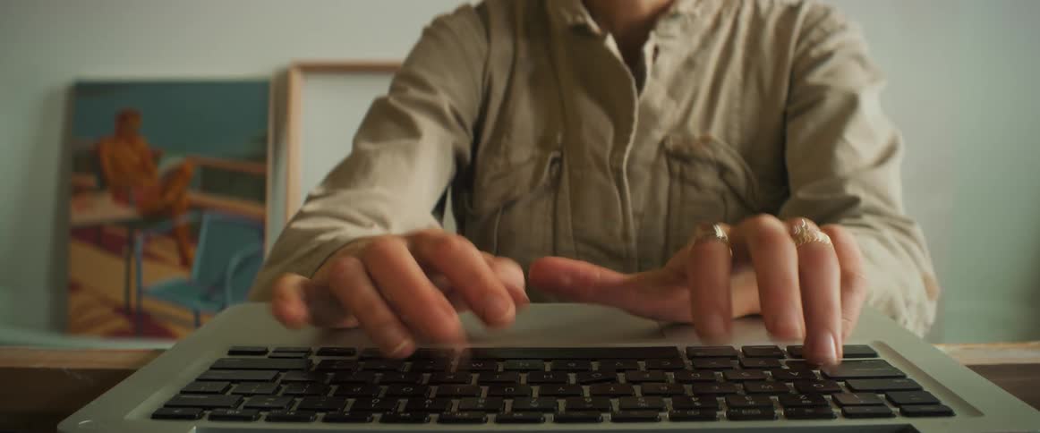 Closeup of a womans hands typing on a laptop