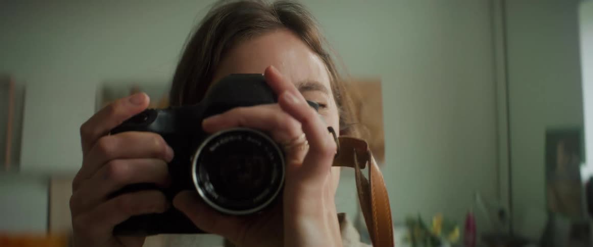 A woman looking through a camera lens