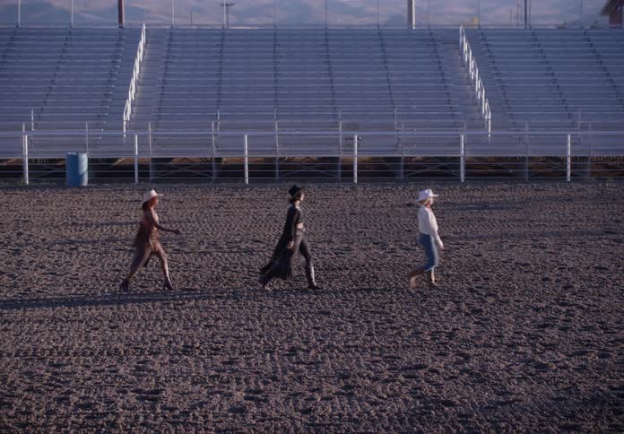 Women parading through a rodeo arena in fashionable cowboy outfits