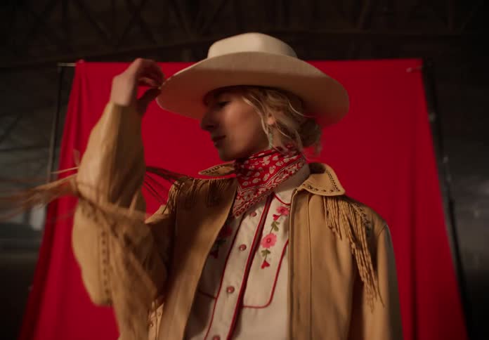 Woman wearing cowboy clothes models in a stable