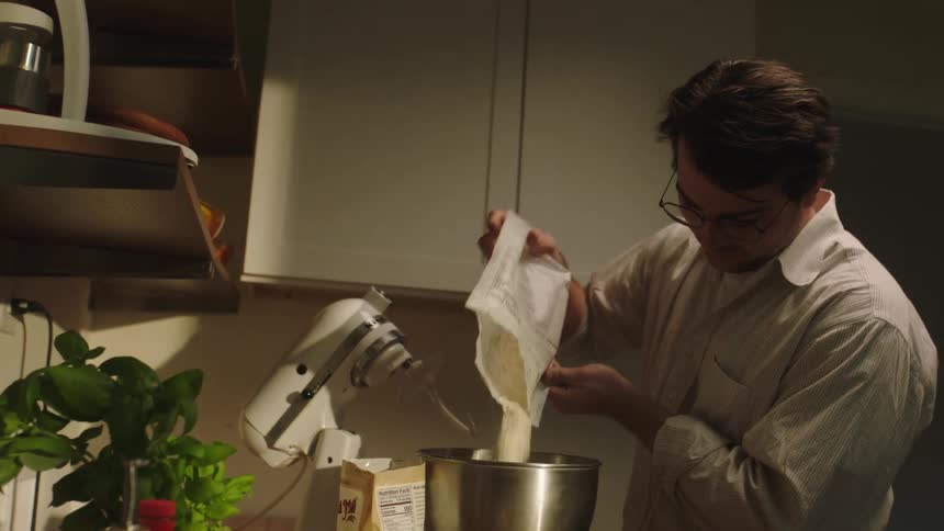 Man pours flour on a mixer in the kitchen