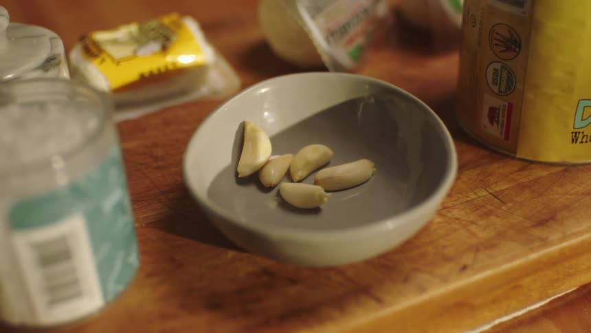 A bowl with peeled garlic on a wooden table
