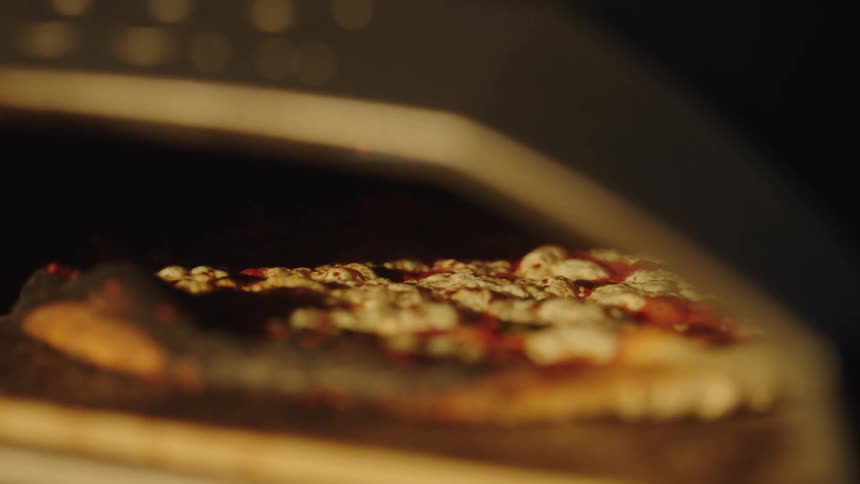 Closeup of a pizza baking with the sauce bubbling