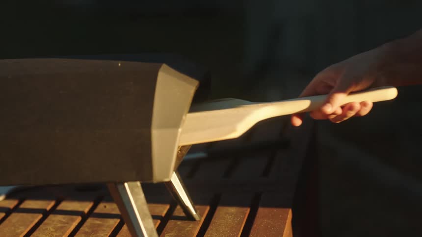 A person putting a pizza to bake in the oven