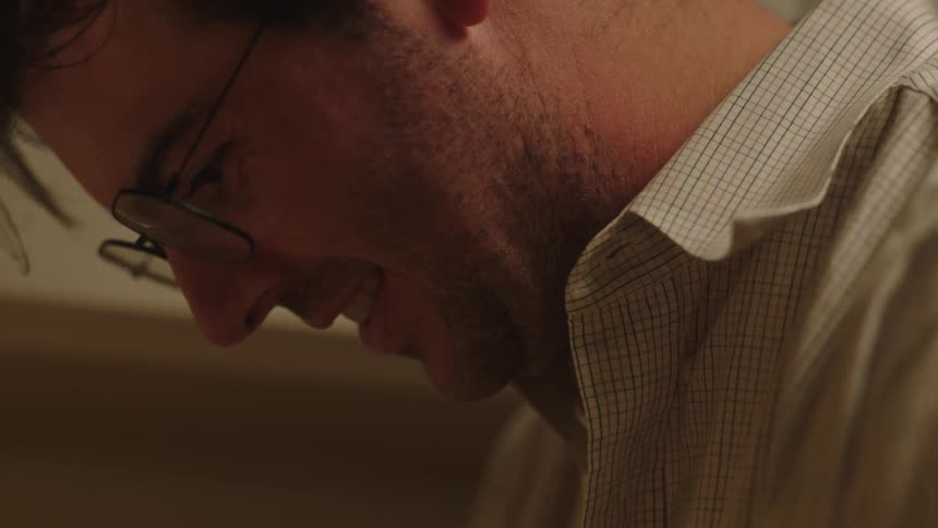 Close up of man in white shirt and glasses looking down in the kitchen