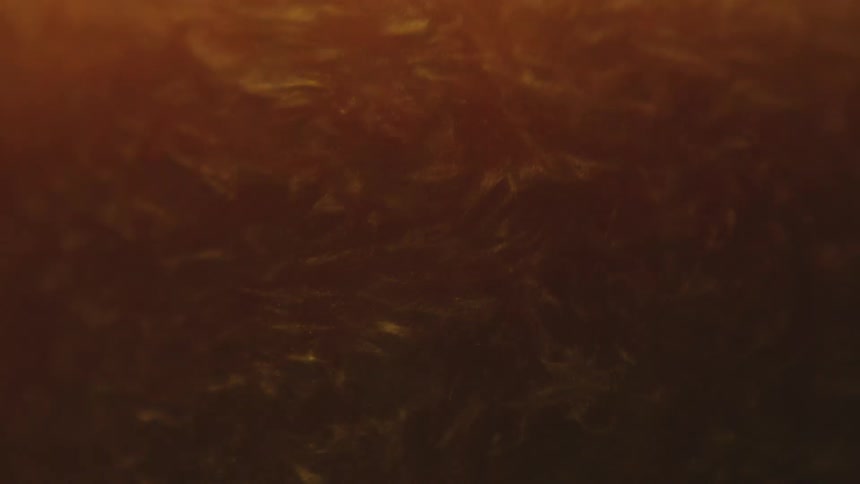 Thick amber shimmering liquid swirling