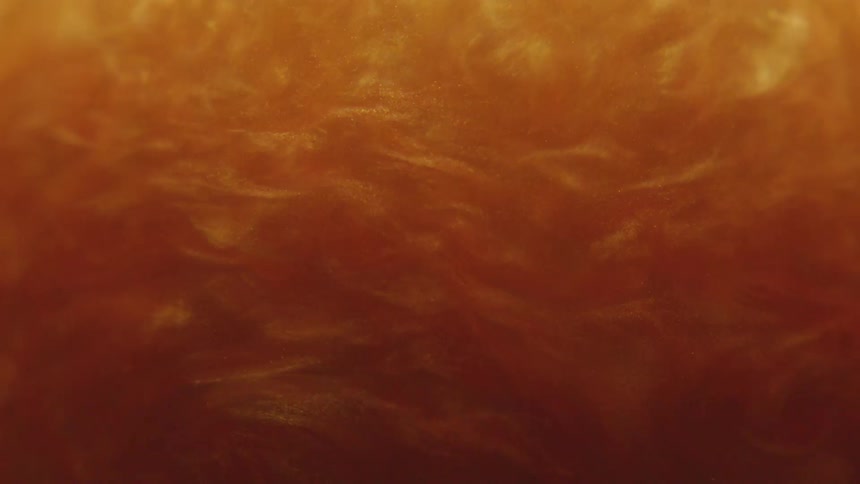 Extreme closeup of golden fluid in slow motion