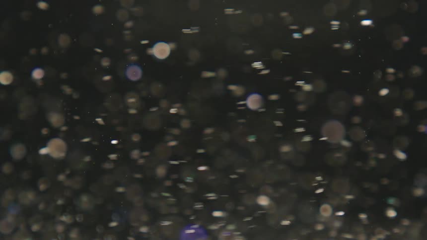 Water with shiny confetti swirling in slow motion
