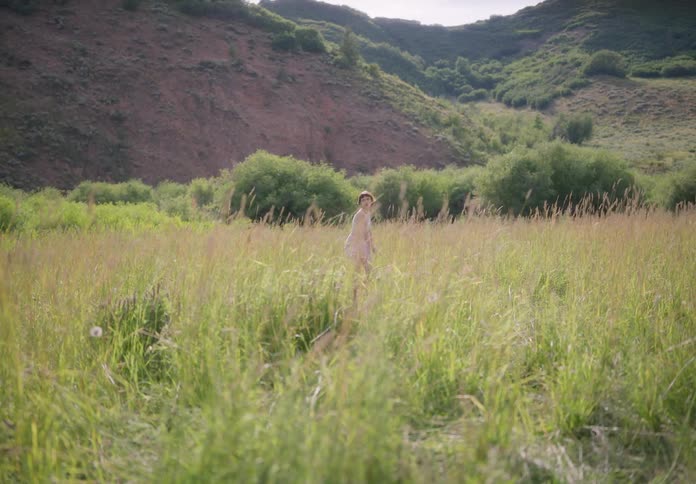 A woman dancing in a pasture during a sunny day