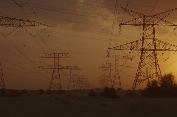 Transmission towers in a field on a day with a reddish sky