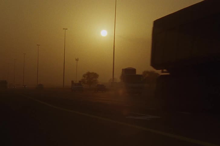 Vehicles traveling along a foggy road in the early hours of the morning