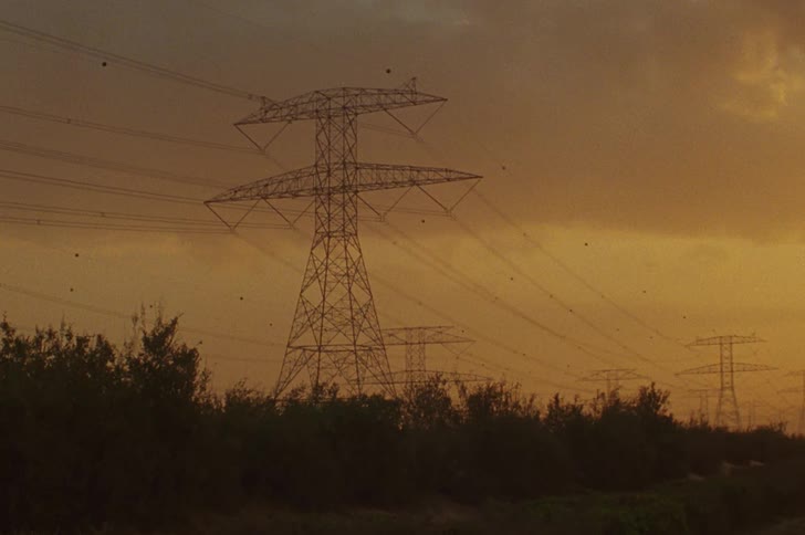 Electric power towers in a natural setting with an orange sky