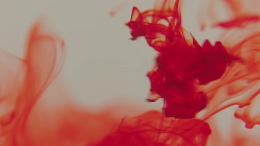 Red paint dripping and dissolving in water
