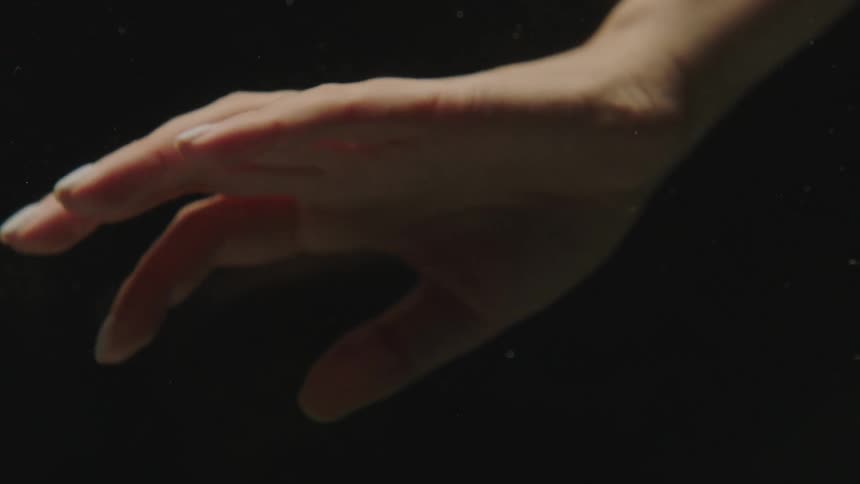 Close up of the hand of a woman against a black background